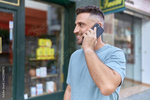Young hispanic man smiling confident talking on the smartphone at street