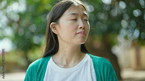 Young chinese woman breathing with closed eyes at park © Krakenimages.com