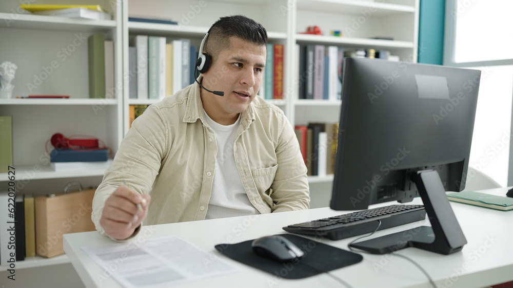 Young hispanic man student having video call writing on document at library university Young hispanic man student having video call writing on document at library university