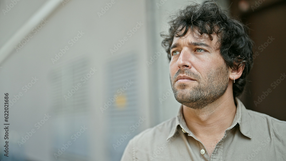 Naklejka premium Young hispanic man looking to the side with serious expression at street