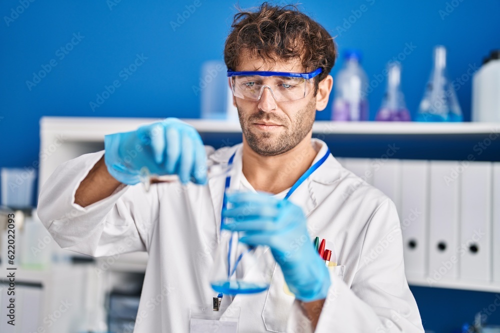Young man scientist pouring liquid on test tube at laboratory Young man scientist pouring liquid on test tube at laboratory