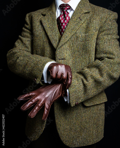 Portrait of Man in Tweed Suit Pulling on Leather Gloves. Vintage Style and Retro Fashion of British Gentleman.