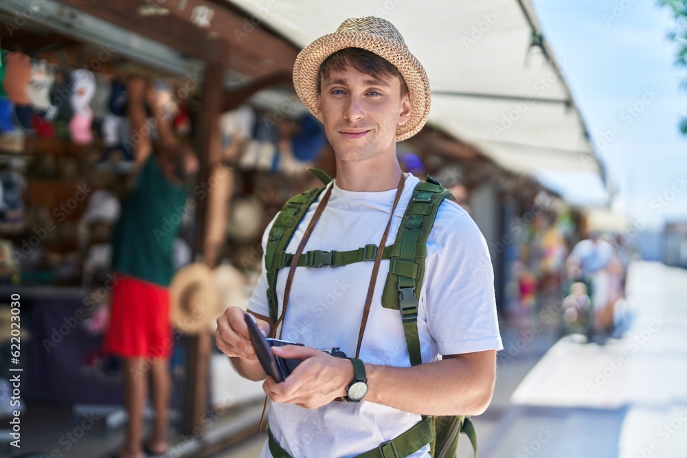 Young caucasian man tourist smiling confident holding wallet with dollars at street market Young caucasian man tourist smiling confident holding wallet with dollars at street market
