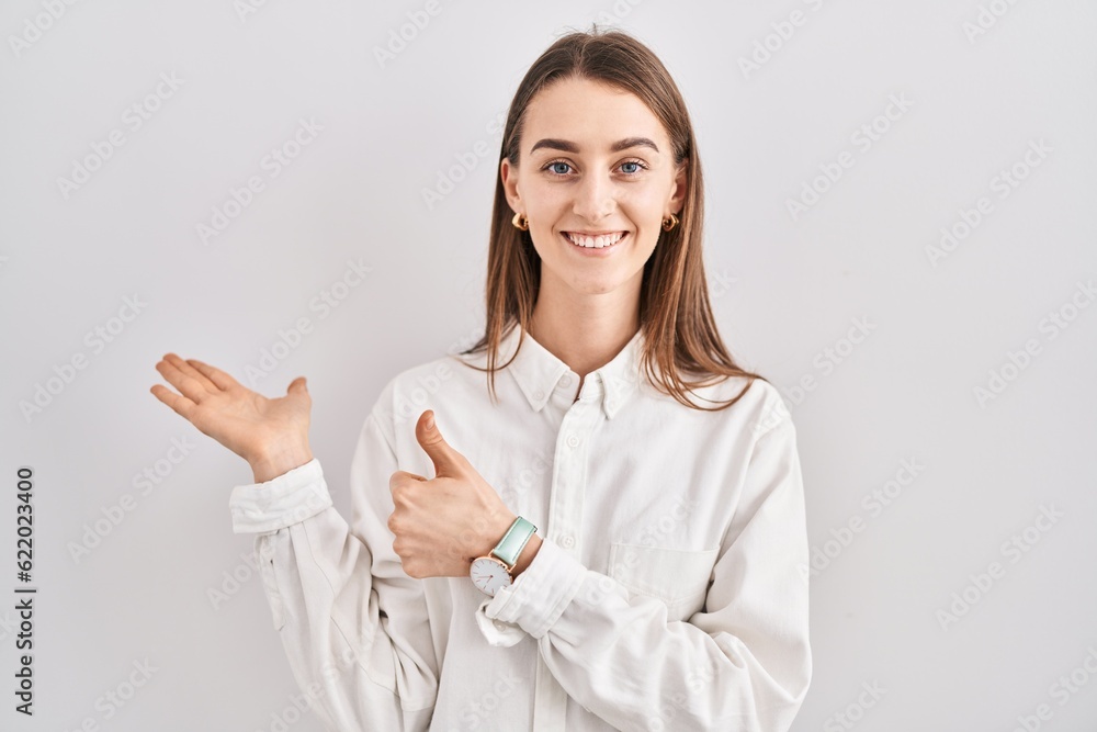 Young caucasian woman standing over isolated background showing palm hand and doing ok gesture with thumbs up, smiling happy and cheerful Young caucasian woman standing over isolated background showing palm hand and doing ok gesture with thumbs up, smiling happy and cheerful