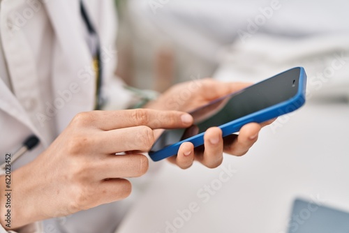 Young caucasian woman doctor using smartphone working at clinic