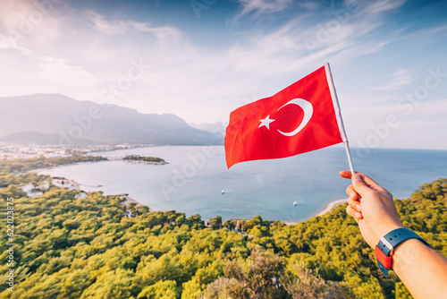 Fototapeta Naklejka Na Ścianę i Meble -  Turkish flag in hand against stunning view of Kemer sea coast and Taurus mountains