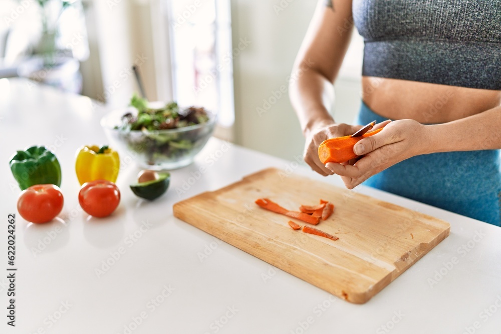 Young woman cutting carrot for salad at kitchen Young woman cutting carrot for salad at kitchen