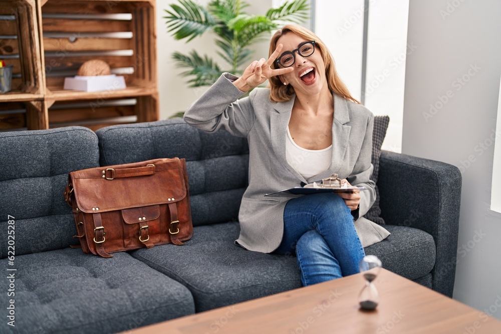 Hispanic woman working at consultation office doing peace symbol with fingers over face, smiling cheerful showing victory Hispanic woman working at consultation office doing peace symbol with fingers over face, smiling cheerful showing victory