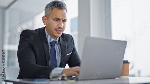 Young hispanic man business worker using laptop at office