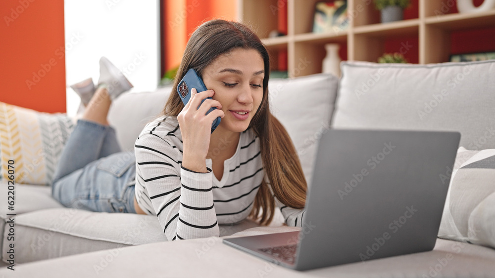 Young beautiful hispanic woman using laptop talking on smartphone at home Young beautiful hispanic woman using laptop talking on smartphone at home