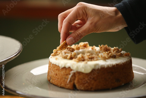 Detalhes que fazem a diferença. Uma delicada mão feminina finaliza a cobertura do bolo com uma noz, trazendo um toque especial e saboroso.