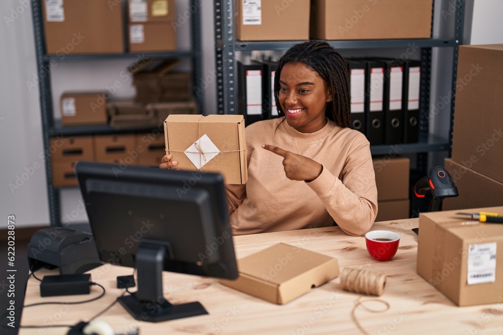 African american woman ecommerce business worker having video call holding package at office African american woman ecommerce business worker having video call holding package at office
