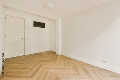 an empty room with white walls and wood flooring on the right side, there is a tv mounted in the wall