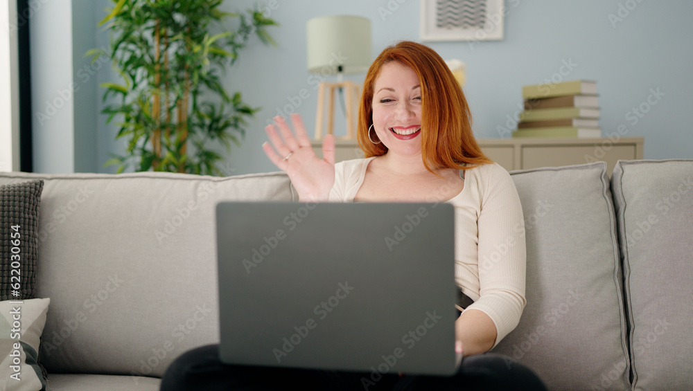 Young redhead woman having video call sitting on sofa at home Young redhead woman having video call sitting on sofa at home