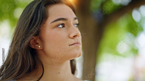 Young beautiful hispanic woman looking to the side with serious expression at park