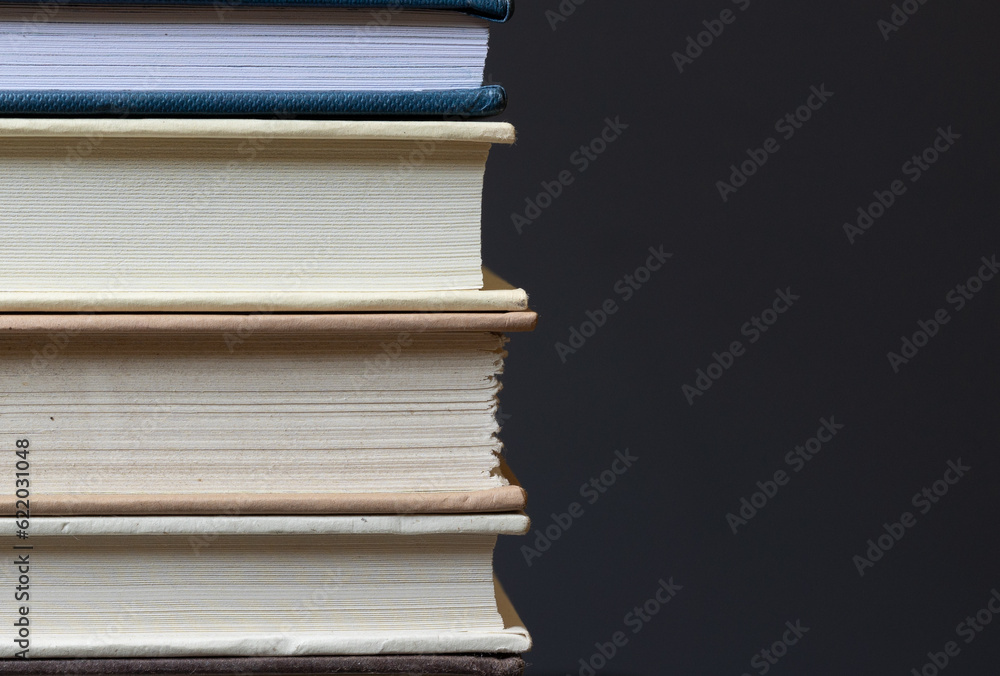 stack of hardcover books in front of dark background with space for copy stack of hardcover books in front of dark background with space for copy