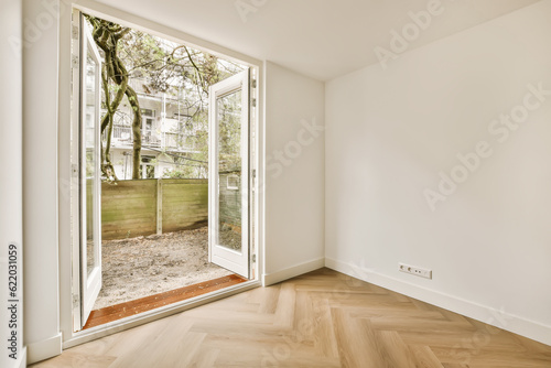 an empty room with wood flooring and large sliding glass door that opens to the backyard garden area in the background