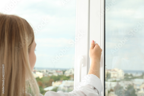 A woman's hand opens a window with a view of the city Free Download A woman's hand opens a window with a view of the city - GFXLoad