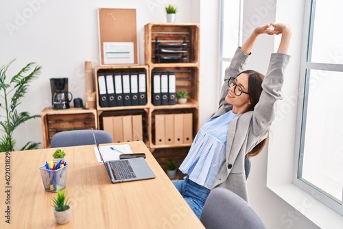 Young beautiful hispanic woman business worker relaxed stretching arms at office