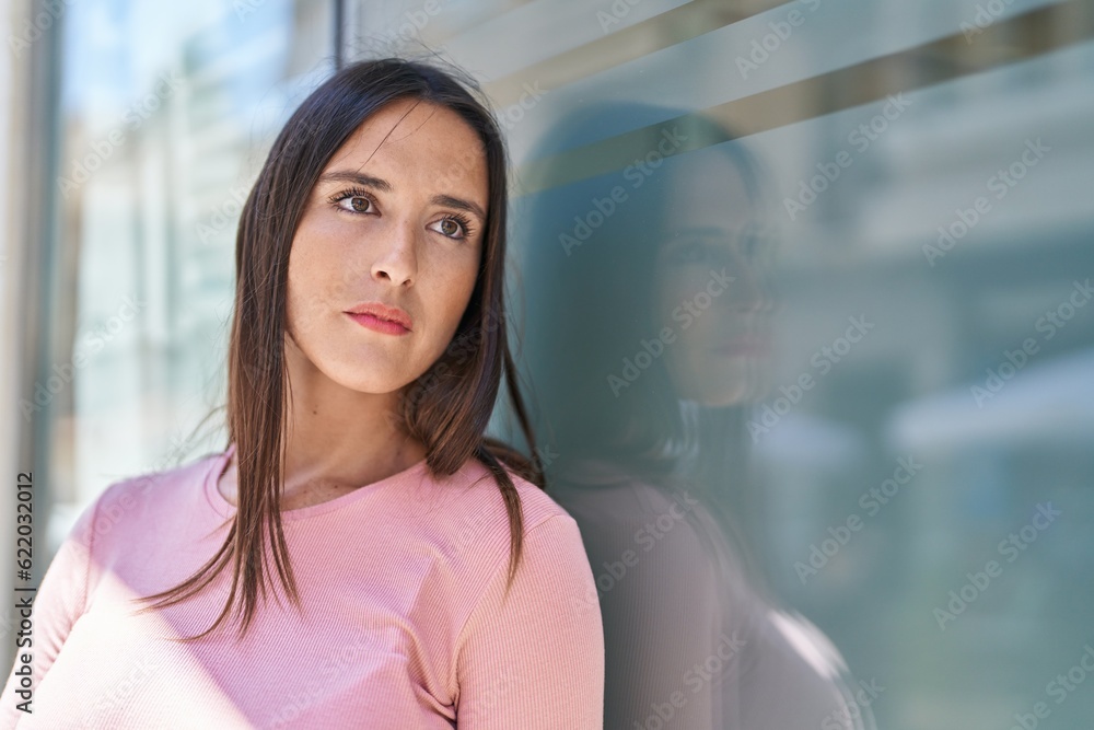 Young beautiful hispanic woman looking to the side with serious expression at street