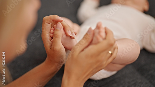 Mother and daughter holding feet at home