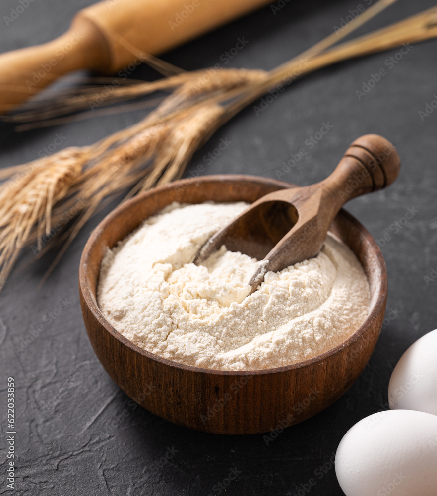 Organic baking ingredients. Wheat flour, eggs and rolling pin on a dark background close up. Concept of homemade and healthy food Organic baking ingredients. Wheat flour, eggs and rolling pin on a dark background close up. Concept of homemade and healthy food