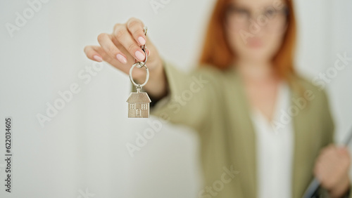 Young redhead woman real state agent holding keys at home