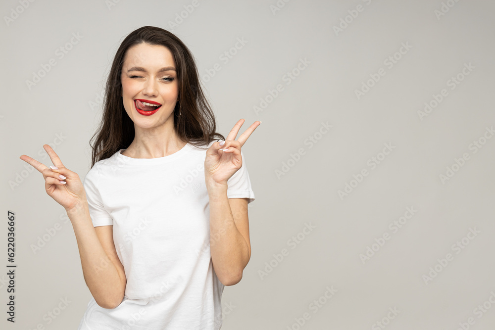 An attractive brunette winks and shows a peace gesture An attractive brunette winks and shows a peace gesture