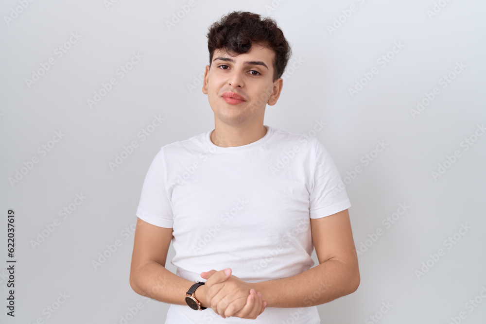 Young non binary man wearing casual white t shirt with hands together and crossed fingers smiling relaxed and cheerful. success and optimistic Young non binary man wearing casual white t shirt with hands together and crossed fingers smiling relaxed and cheerful. success and optimistic