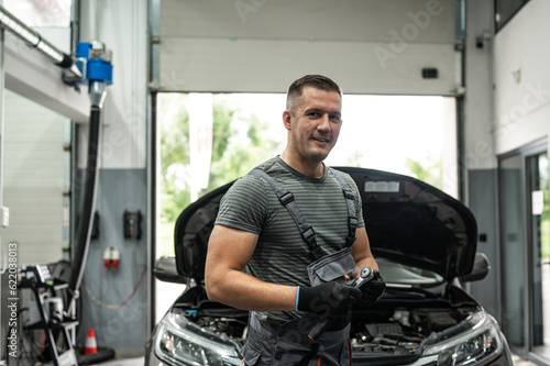 portrait of a mechanic in front of his workshop