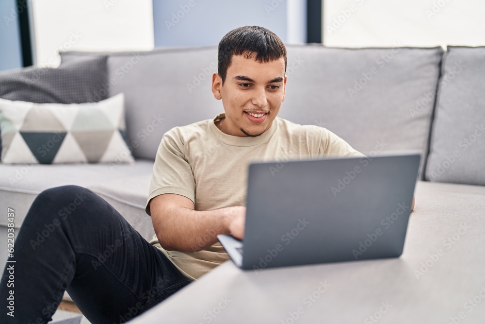 Young man using laptop sitting on floor at home Young man using laptop sitting on floor at home