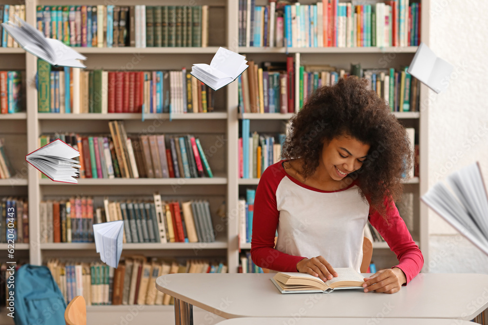 African-American student preparing for exam in library with flying books African-American student preparing for exam in library with flying books