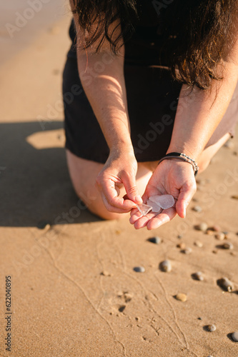 Close up of woman's hands collecting beach glass on sandy shore