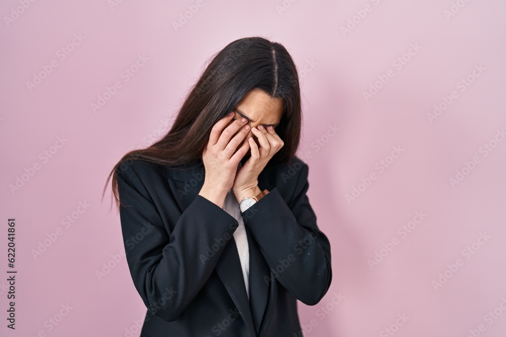Young brunette woman wearing business style over pink background rubbing eyes for fatigue and headache, sleepy and tired expression. vision problem Young brunette woman wearing business style over pink background rubbing eyes for fatigue and headache, sleepy and tired expression. vision problem