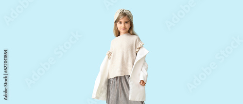 Cute little girl in stylish autumn clothes on light blue background
