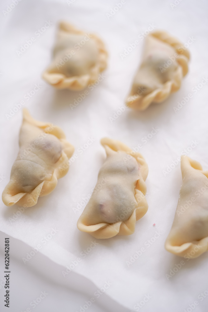 Close-up, top view of ready-made raw Ukrainian traditional varenyki ready to cook on baking paper. Traditional Ukrainian recipes Close-up, top view of ready-made raw Ukrainian traditional varenyki ready to cook on baking paper. Traditional Ukrainian recipes