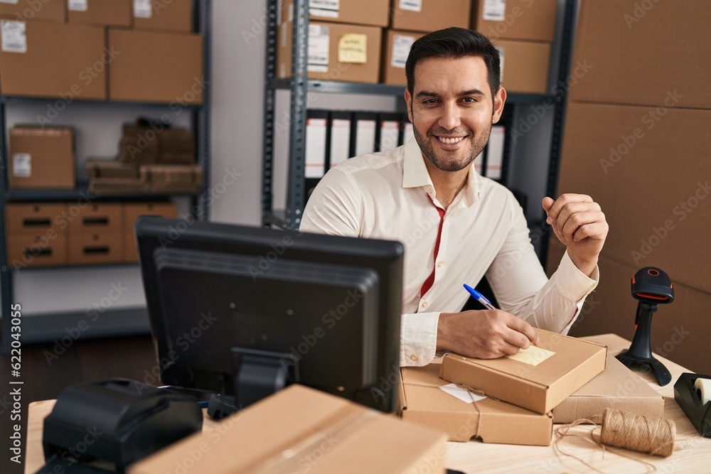 Young hispanic man e-commerce business worker write on package at office Young hispanic man e-commerce business worker write on package at office