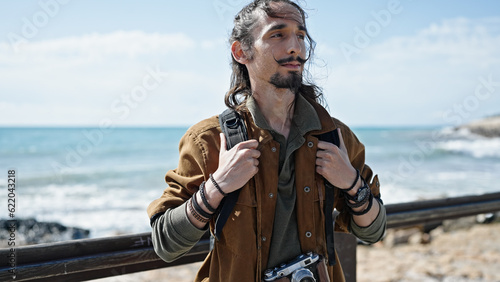 Young hispanic man tourist wearing backpack at seaside