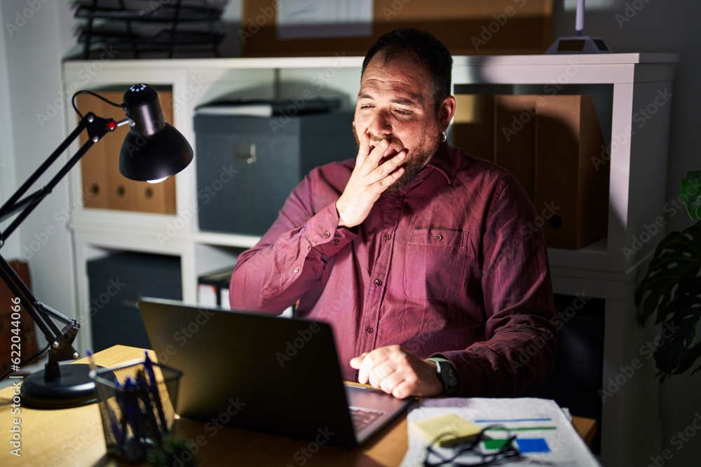 Plus size hispanic man with beard working at the office at night bored yawning tired covering mouth with hand. restless and sleepiness. Plus size hispanic man with beard working at the office at night bored yawning tired covering mouth with hand. restless and sleepiness.