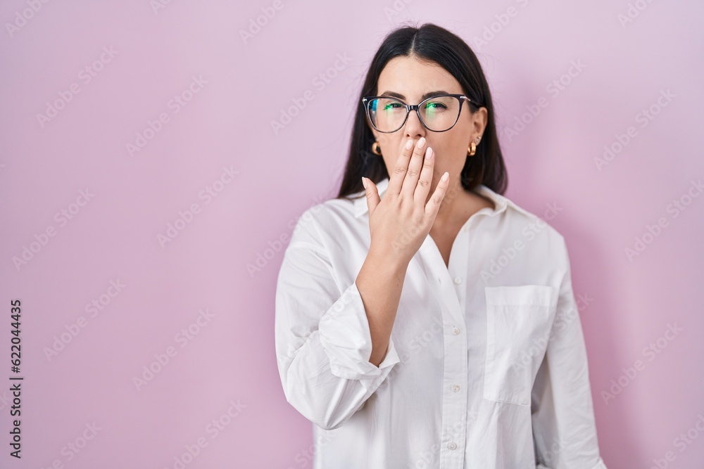 Young brunette woman standing over pink background bored yawning tired covering mouth with hand. restless and sleepiness. Young brunette woman standing over pink background bored yawning tired covering mouth with hand. restless and sleepiness.