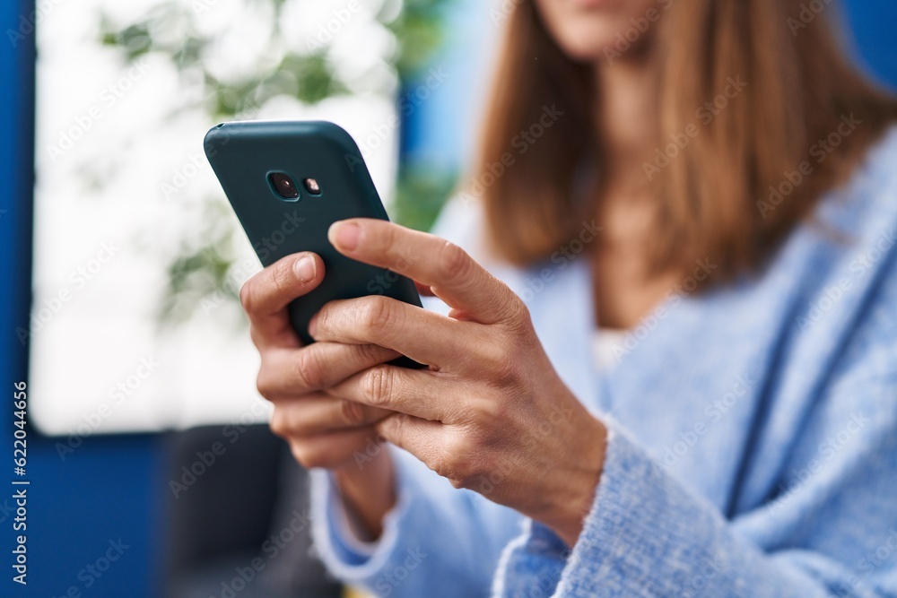 Young woman using smartphone sitting on sofa at home Young woman using smartphone sitting on sofa at home