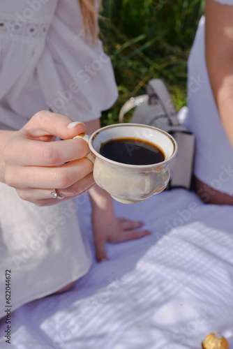 woman holding cup of coffee on the picnic