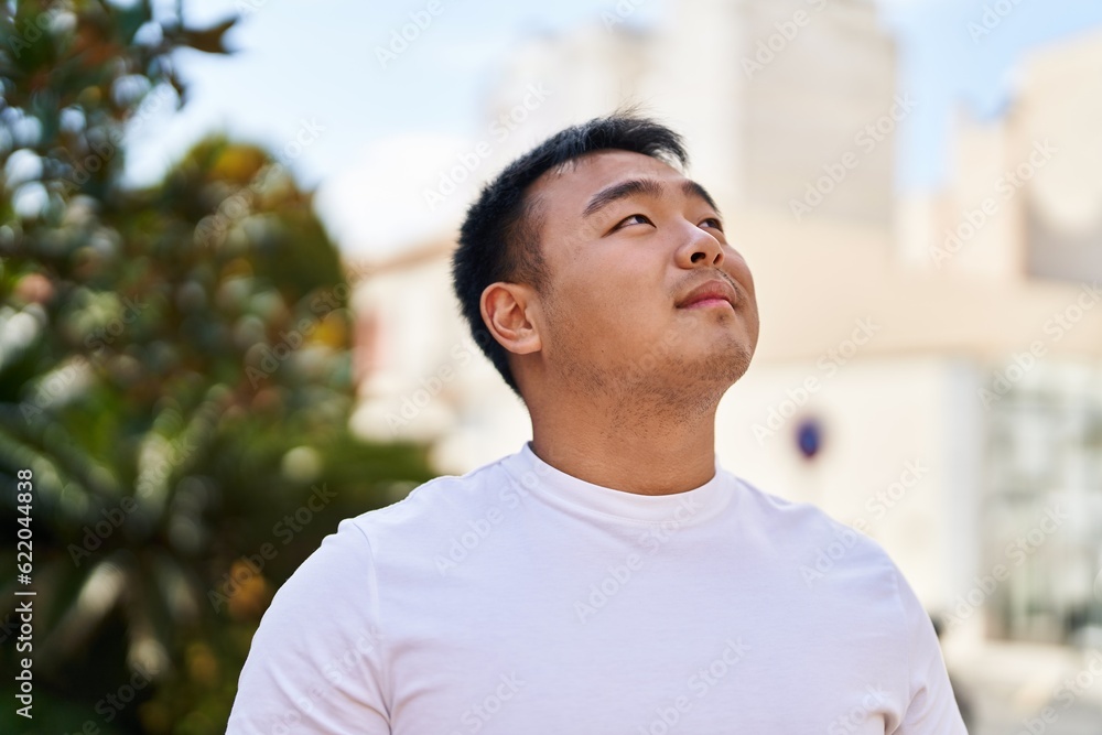 Young chinese man smiling confident looking to the sky at street Young chinese man smiling confident looking to the sky at street