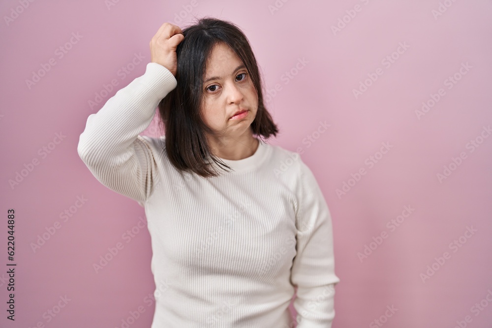 Woman with down syndrome standing over pink background confuse and wondering about question. uncertain with doubt, thinking with hand on head. pensive concept. Woman with down syndrome standing over pink background confuse and wondering about question. uncertain with doubt, thinking with hand on head. pensive concept.