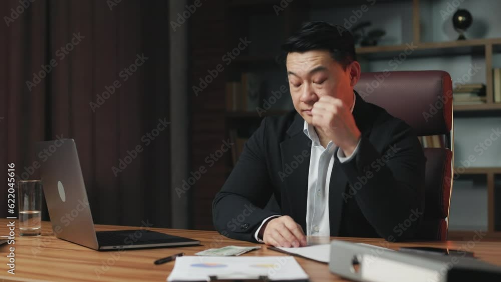 Anxious entrepreneur feeling upset due to lack of money. Pensive asian worker with sad face expression sitting in comfortable office chair and thinking how to get more cash. Anxious entrepreneur feeling upset due to lack of money. Pensive asian worker with sad face expression sitting in comfortable office chair and thinking how to get more cash.
