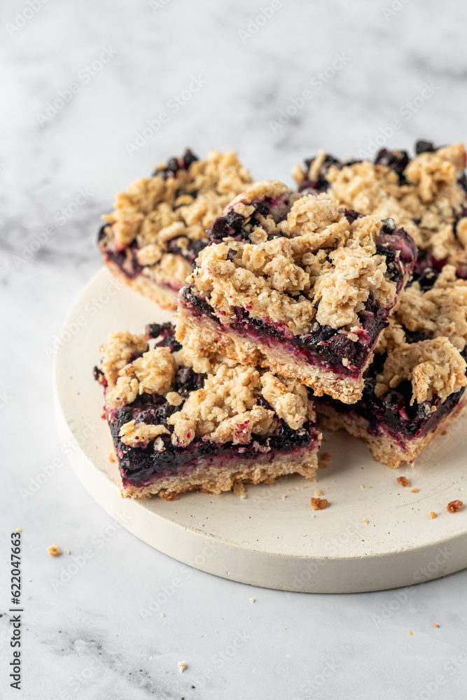 Vegan baked oatmeal squares with fresh blueberry on white tray on marble background
