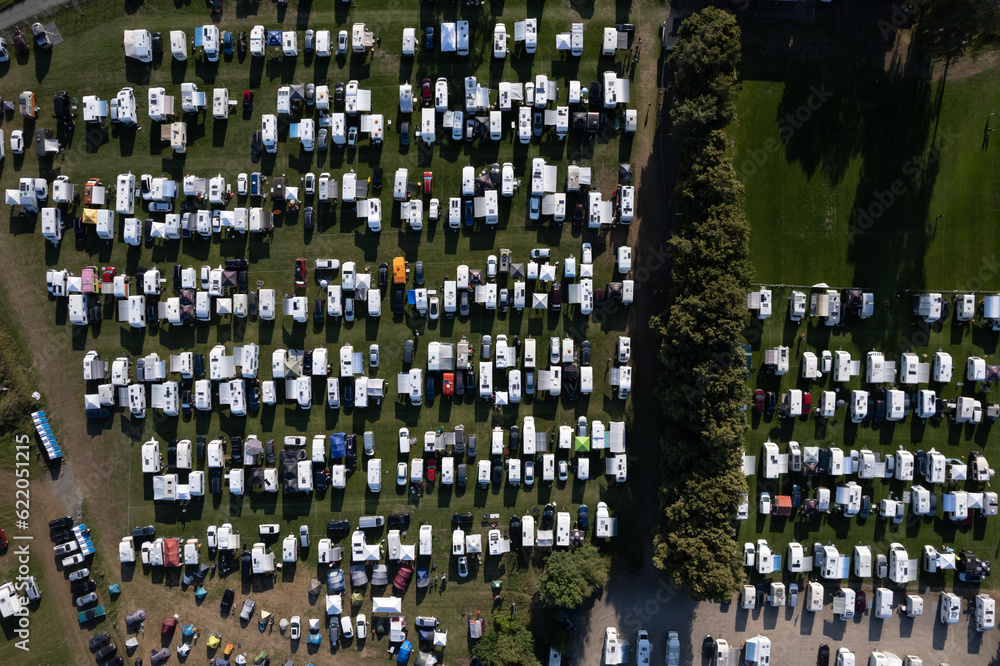 Drone view of a lot of mobile homes, motorhomes, camping vans, tents on a campsite, campground in European village. Holidays, vacation season in summer. Drone view of a lot of mobile homes, motorhomes, camping vans, tents on a campsite, campground in European village. Holidays, vacation season in summer.