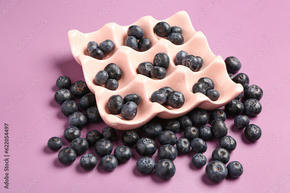 Ice cube tray with fresh blueberries on lilac background Ice cube tray with fresh blueberries on lilac background