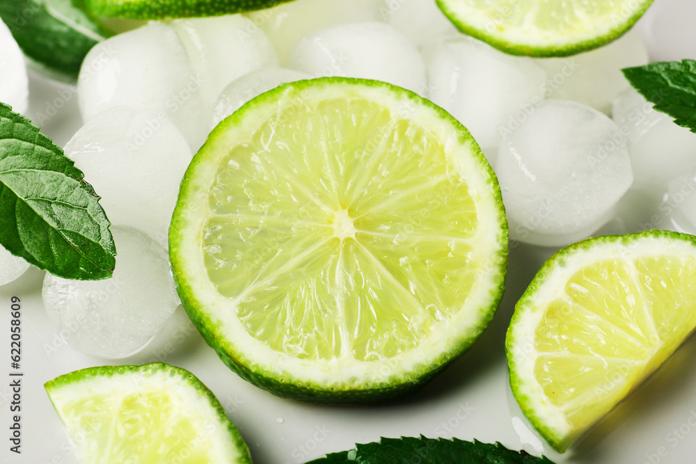 Lime slices with ice cubes and mint on grey background