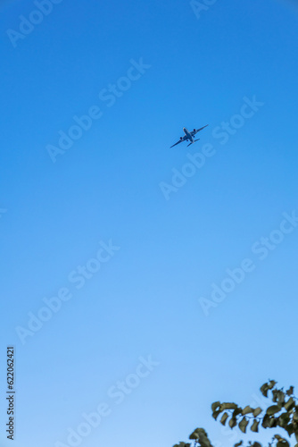 View of airplane flying in blue sky. Vertical photo. High quality photo